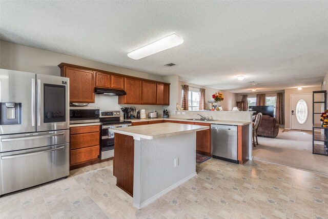 kitchen featuring sink, stainless steel appliances, kitchen peninsula, a textured ceiling, and a kitchen island