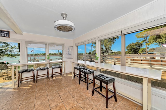 sunroom featuring a wealth of natural light, a water view, and beam ceiling