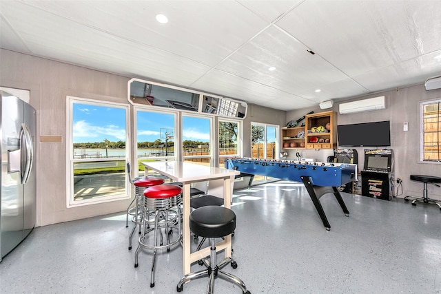 recreation room featuring a wall mounted air conditioner and plenty of natural light