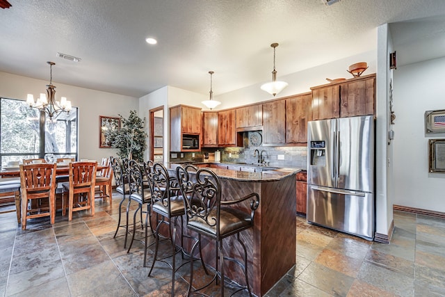 1133 Brackeen Dr, Graford, TX 76449 - kitchen with stainless steel fridge with ice dispenser, stone tile floors, black microwave, backsplash, and a textured ceiling