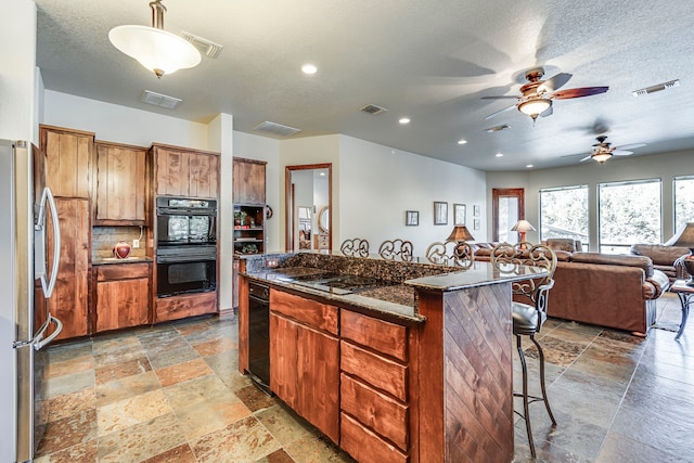 1133 Brackeen Dr, Graford, TX 76449 - kitchen with black appliances, stone tile flooring, a kitchen bar, ceiling fan, and a kitchen island