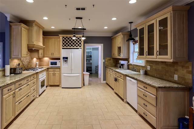 kitchen featuring sink, white appliances, decorative light fixtures, and light stone counters