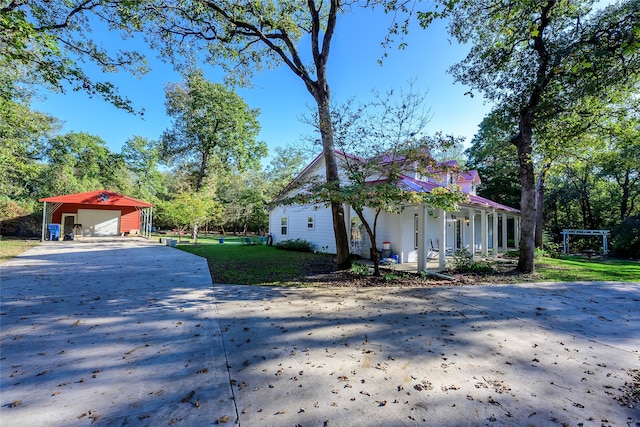 view of front of property with a front lawn, covered porch, a garage, and an outdoor structure