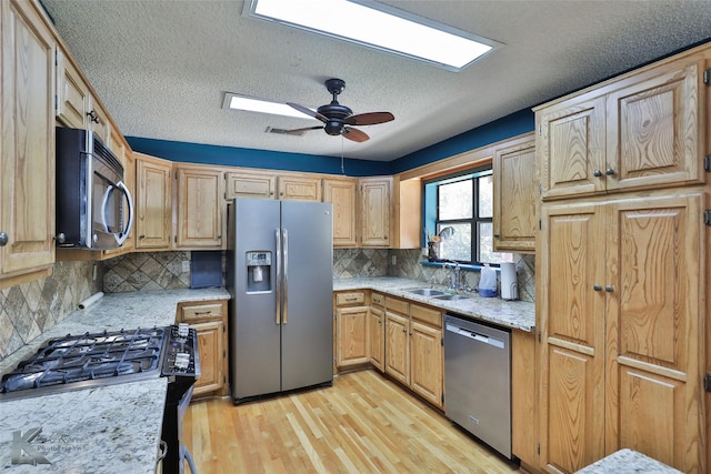 kitchen featuring appliances with stainless steel finishes, a textured ceiling, backsplash, and sink