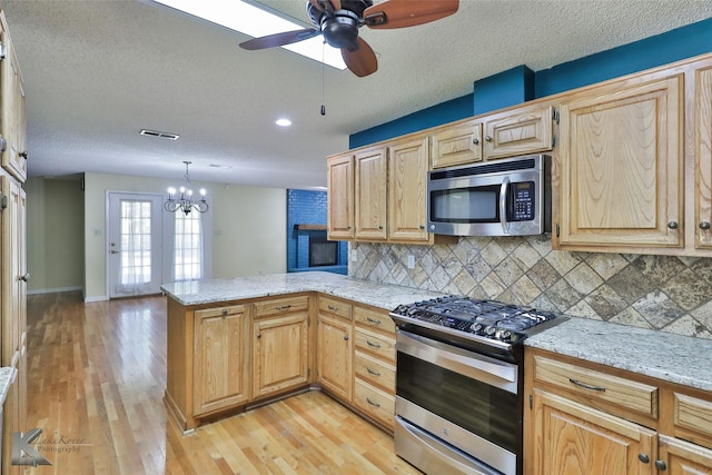 kitchen with backsplash, kitchen peninsula, stainless steel appliances, and a textured ceiling