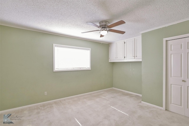 unfurnished room featuring ceiling fan, light colored carpet, and a textured ceiling