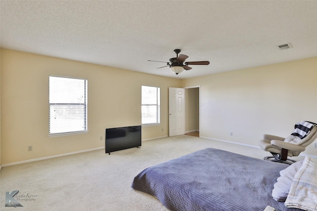 carpeted bedroom with multiple windows, ceiling fan, and a textured ceiling