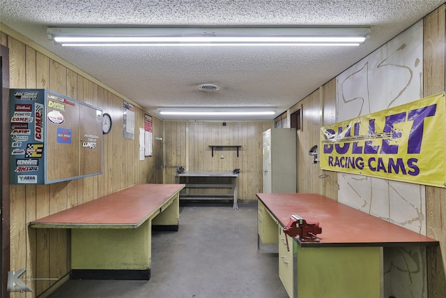 interior space with a textured ceiling and wooden walls