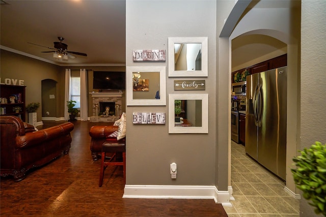 living room with ceiling fan, a fireplace, and ornamental molding