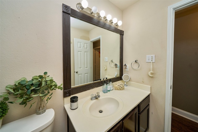 bathroom with wood-type flooring, vanity, and toilet