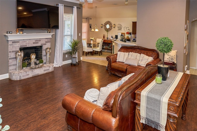 living room with a notable chandelier, wood-type flooring, and a brick fireplace