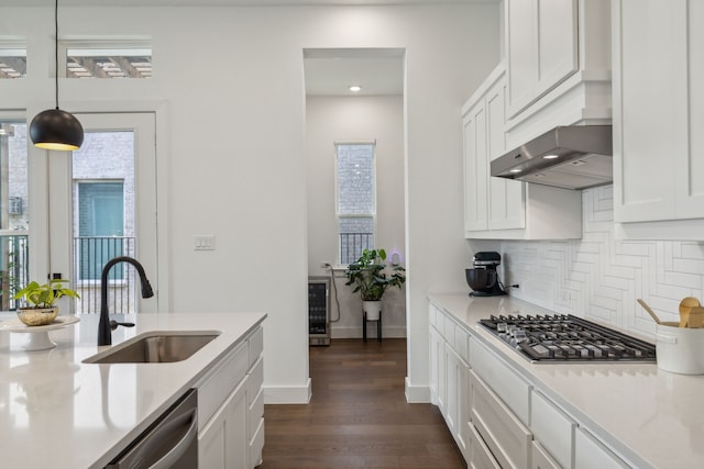 kitchen with sink, stainless steel appliances, backsplash, pendant lighting, and white cabinets