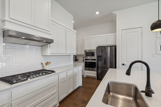 kitchen featuring white cabinetry, sink, stainless steel appliances, tasteful backsplash, and decorative light fixtures