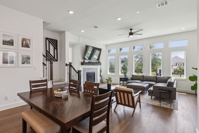 dining space with ceiling fan, dark hardwood / wood-style flooring, and a fireplace