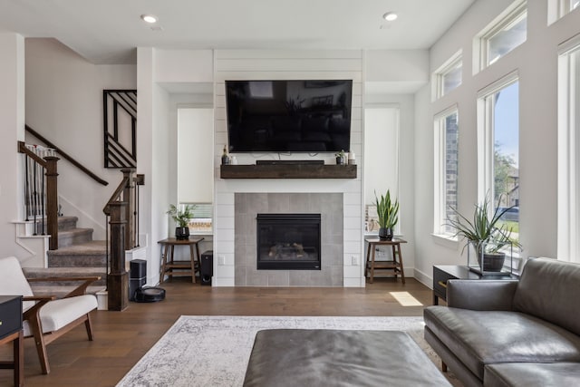 living room with dark wood-type flooring and a tiled fireplace