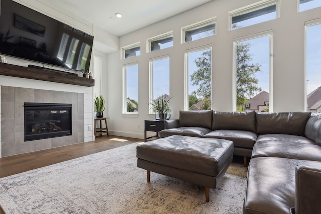 living room with a tile fireplace and dark wood-type flooring