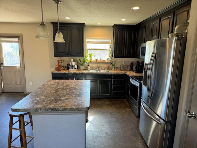 kitchen with appliances with stainless steel finishes, decorative light fixtures, plenty of natural light, and a kitchen island