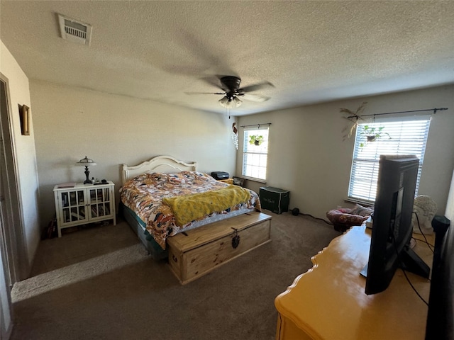 bedroom featuring multiple windows, a textured ceiling, ceiling fan, and dark carpet