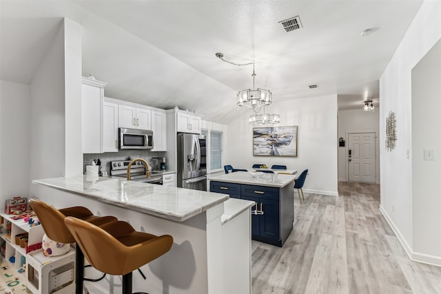 kitchen with stainless steel appliances, blue cabinets, kitchen peninsula, pendant lighting, and white cabinets