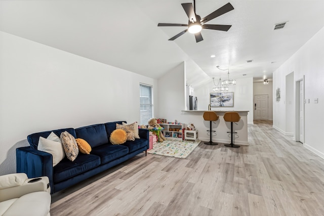 living room with ceiling fan with notable chandelier, lofted ceiling, and light hardwood / wood-style flooring