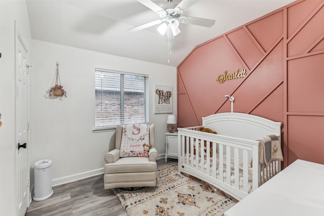 bedroom featuring ceiling fan, a crib, and hardwood / wood-style flooring