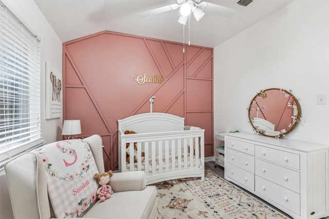 bedroom featuring multiple windows, ceiling fan, a nursery area, and light hardwood / wood-style floors