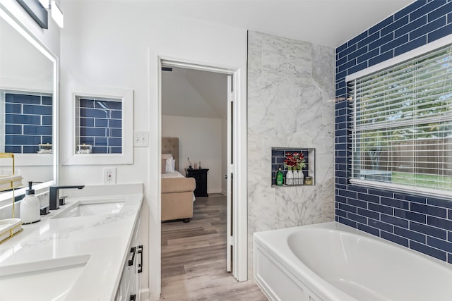 bathroom with hardwood / wood-style floors, vanity, a healthy amount of sunlight, and a bath