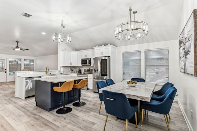 dining area with ceiling fan, sink, lofted ceiling, and light hardwood / wood-style flooring