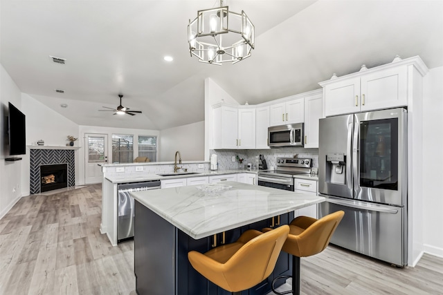 kitchen featuring sink, vaulted ceiling, a kitchen island, kitchen peninsula, and stainless steel appliances