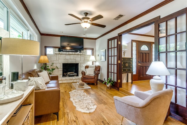 living room with a fireplace, ceiling fan, light hardwood / wood-style floors, and crown molding