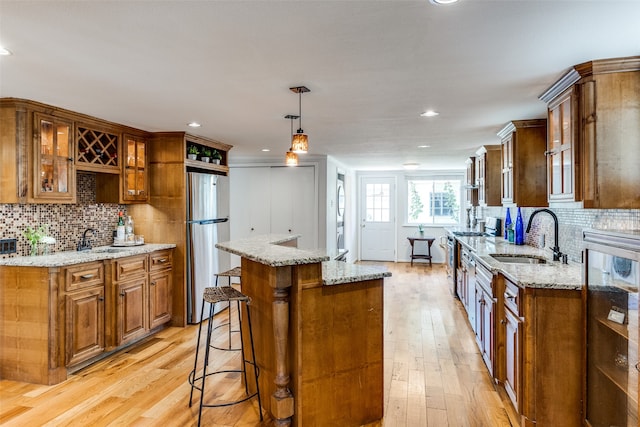 kitchen featuring light wood-type flooring, appliances with stainless steel finishes, decorative light fixtures, sink, and a center island