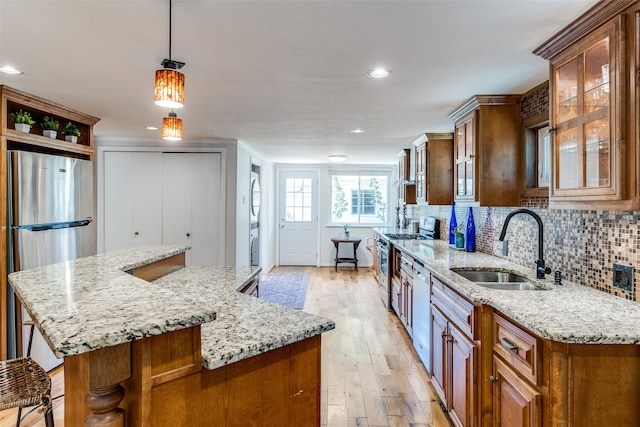 kitchen with stainless steel appliances, light hardwood / wood-style floors, pendant lighting, and light stone counters