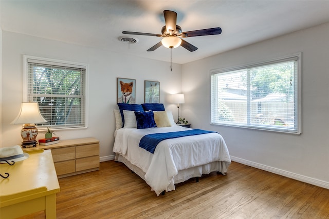 bedroom featuring light wood-type flooring, multiple windows, and ceiling fan