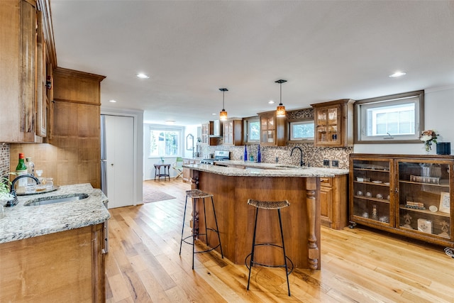 kitchen featuring a center island, a wealth of natural light, decorative light fixtures, and light hardwood / wood-style flooring