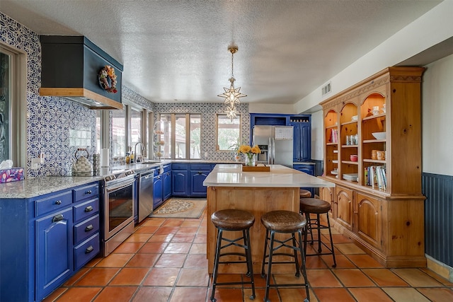 kitchen with stainless steel appliances, blue cabinets, a breakfast bar area, a textured ceiling, and sink