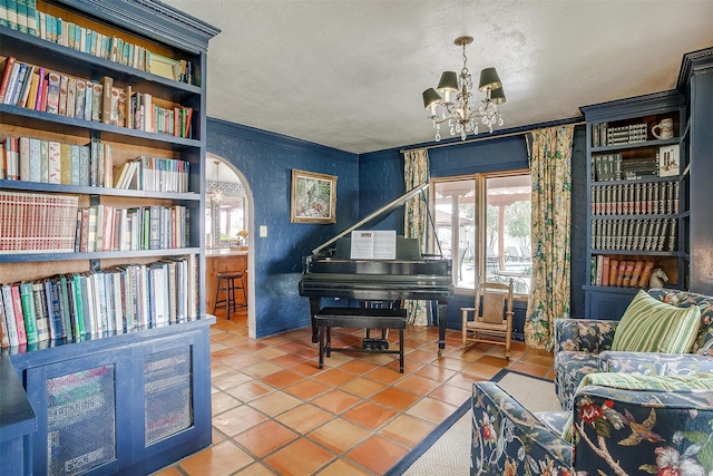 sitting room with a chandelier, a textured ceiling, tile patterned floors, and ornamental molding