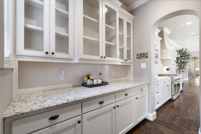 kitchen featuring stainless steel appliances, light stone countertops, white cabinets, and dark wood-type flooring