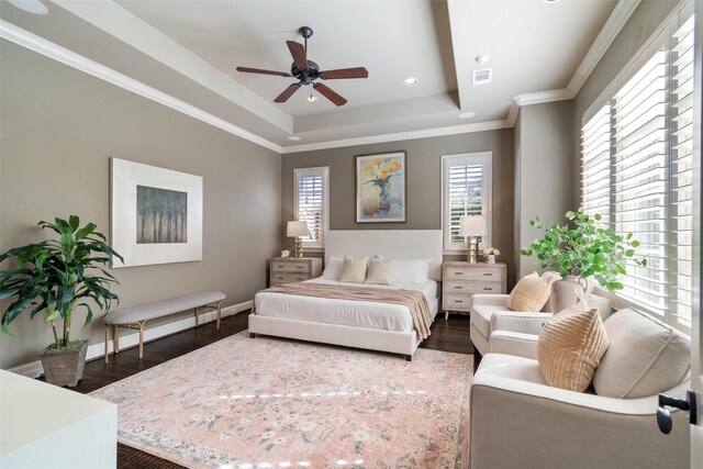 bedroom featuring ornamental molding, dark hardwood / wood-style flooring, ceiling fan, and a tray ceiling