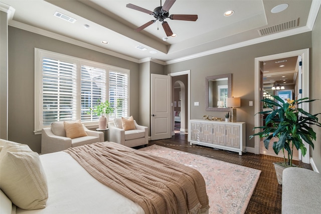 bedroom with dark wood-type flooring, a tray ceiling, ceiling fan, and crown molding