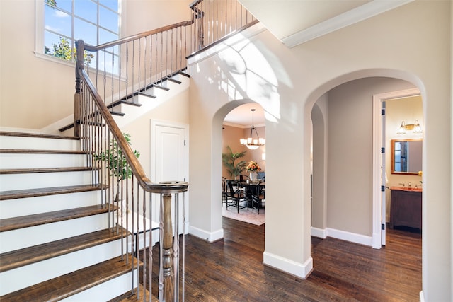 foyer entrance featuring dark wood-type flooring, a chandelier, and ornamental molding