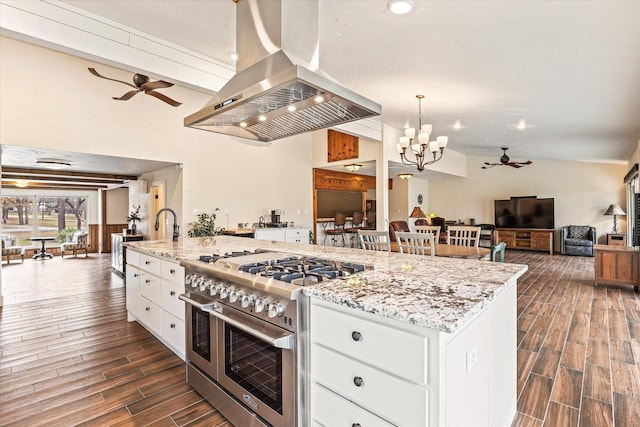 kitchen with white cabinetry, a spacious island, island range hood, ceiling fan with notable chandelier, and range with two ovens