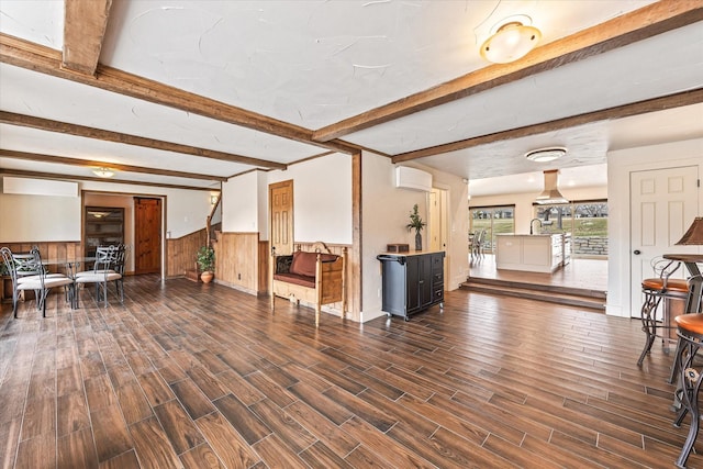 living room with a wall mounted air conditioner, beam ceiling, dark hardwood / wood-style floors, and wooden walls