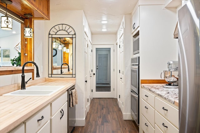 kitchen with sink, white cabinetry, fridge, dark hardwood / wood-style flooring, and decorative light fixtures