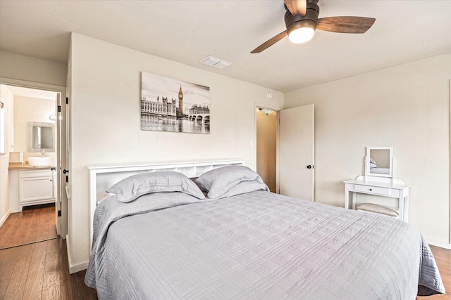 bedroom featuring ceiling fan, sink, dark wood-type flooring, and ensuite bath