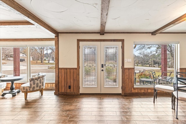 doorway featuring wood walls, french doors, beamed ceiling, and wood-type flooring