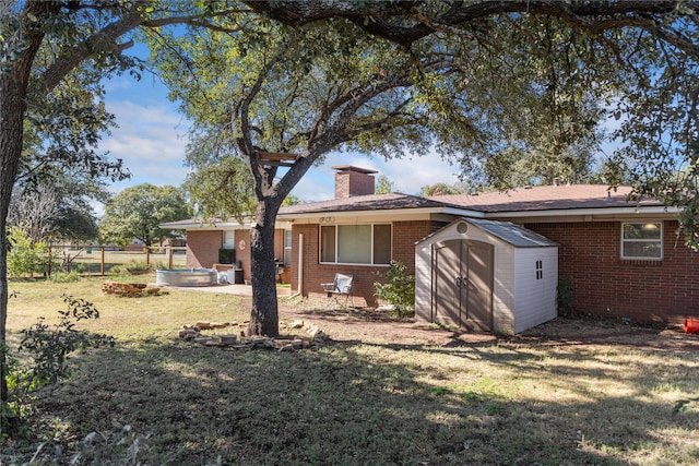 rear view of property with a storage unit and a lawn