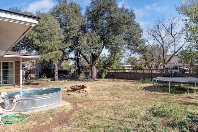 view of yard with a fire pit and a trampoline