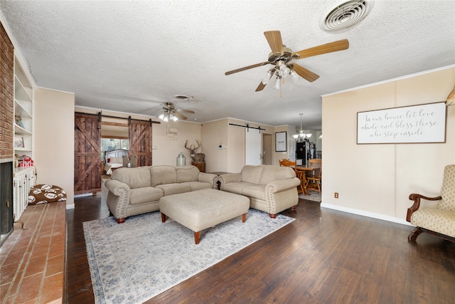 living room featuring a barn door, ceiling fan with notable chandelier, a textured ceiling, and dark hardwood / wood-style flooring