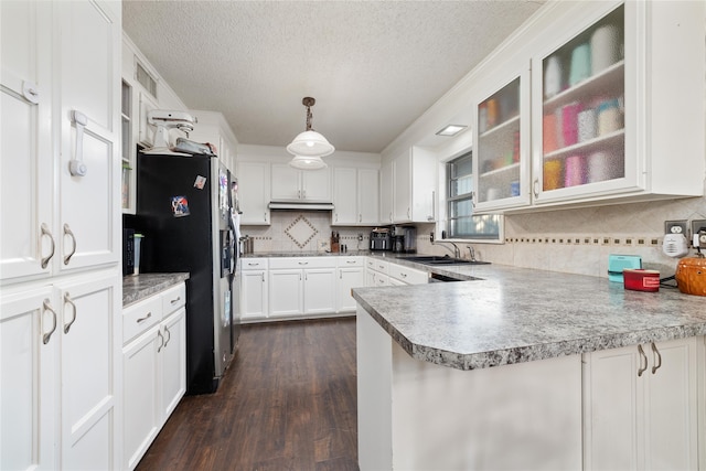 kitchen with a textured ceiling, decorative light fixtures, white cabinets, dark wood-type flooring, and kitchen peninsula