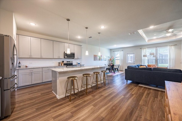 kitchen with a breakfast bar, appliances with stainless steel finishes, open floor plan, and dark wood finished floors